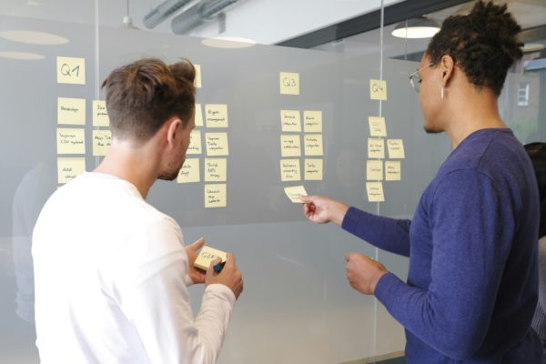 2 personnes réfléchissent et notent des idées sur des post-it jaunes