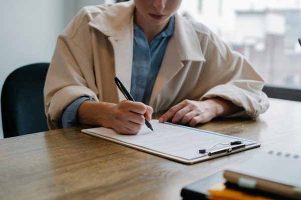Vue d'une femme qui remplit un formulaire papier sur une table