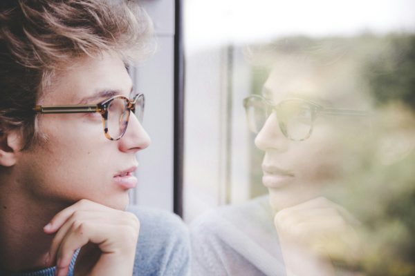 jeune homme en réflexion devant une vitre